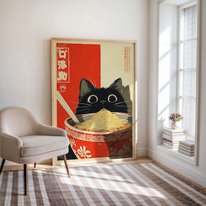 May include: A framed art print featuring a black cat peering over a bowl of ramen noodles. The bowl is red with a floral design. The background is divided into red and beige sections, with Japanese text.