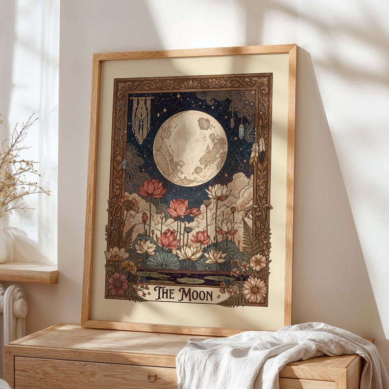May include: A framed art print depicting a full moon, lotus flowers, and a night sky. The artwork has a vintage aesthetic with a colour palette of beige, blue, and pink. The text "THE MOON" is at the bottom of the print.