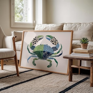 May include: A framed art print featuring a colorful crab illustration. The crab is depicted in shades of green, blue, and black, with a detailed pattern. The artwork is displayed in a light-colored wooden frame, suitable for coastal or nautical decor.