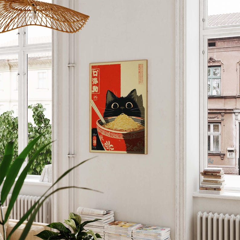 May include: A framed art print featuring a black cat peering over a bowl of noodles. The cat's eyes are large and round. The bowl is red with a white floral design. The background is red and beige with Japanese text.