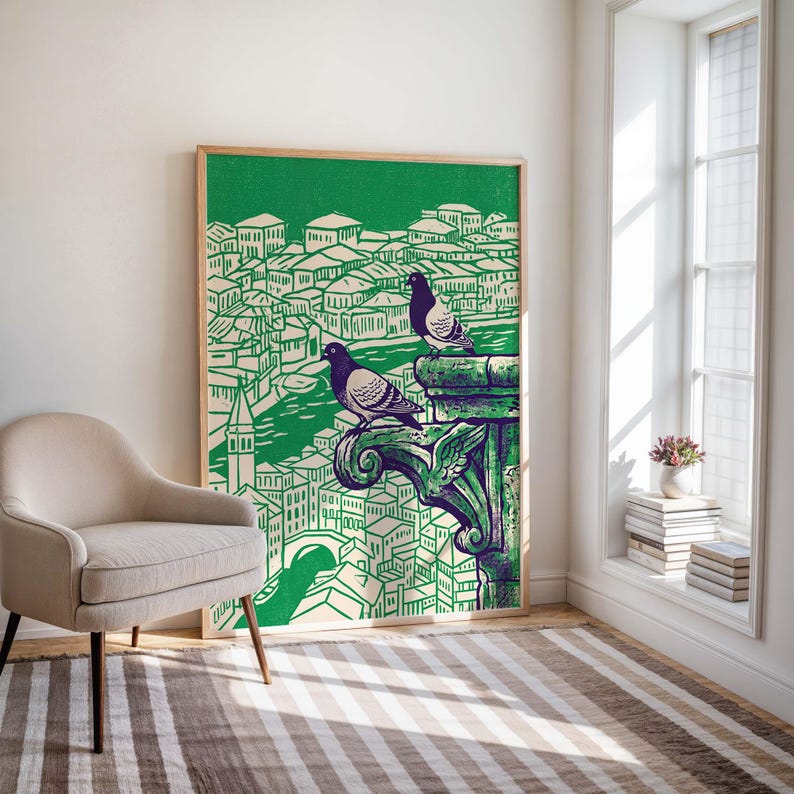 May include: A framed art print featuring a green and white illustration of a cityscape with two pigeons perched on a decorative element. The artwork has a vintage aesthetic, with a wooden frame and a green background.