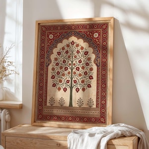 May include: Framed art print featuring a stylized tree with red pomegranates. The artwork has a beige background with a decorative red and blue border. The wooden frame adds a natural touch to the piece.