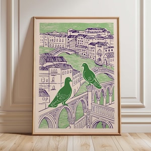 May include: A framed art print featuring a green and purple illustration of a cityscape with two green pigeons perched on a bridge. The artwork depicts buildings, bridges, and water, with a light green background and a wooden frame.