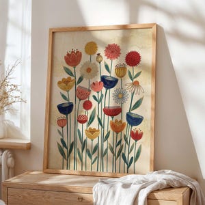 May include: A framed art print featuring a colorful floral illustration. The artwork showcases a variety of stylized flowers in shades of red, yellow, blue, and pink, set against a beige background. The print is encased in a light brown wooden frame.