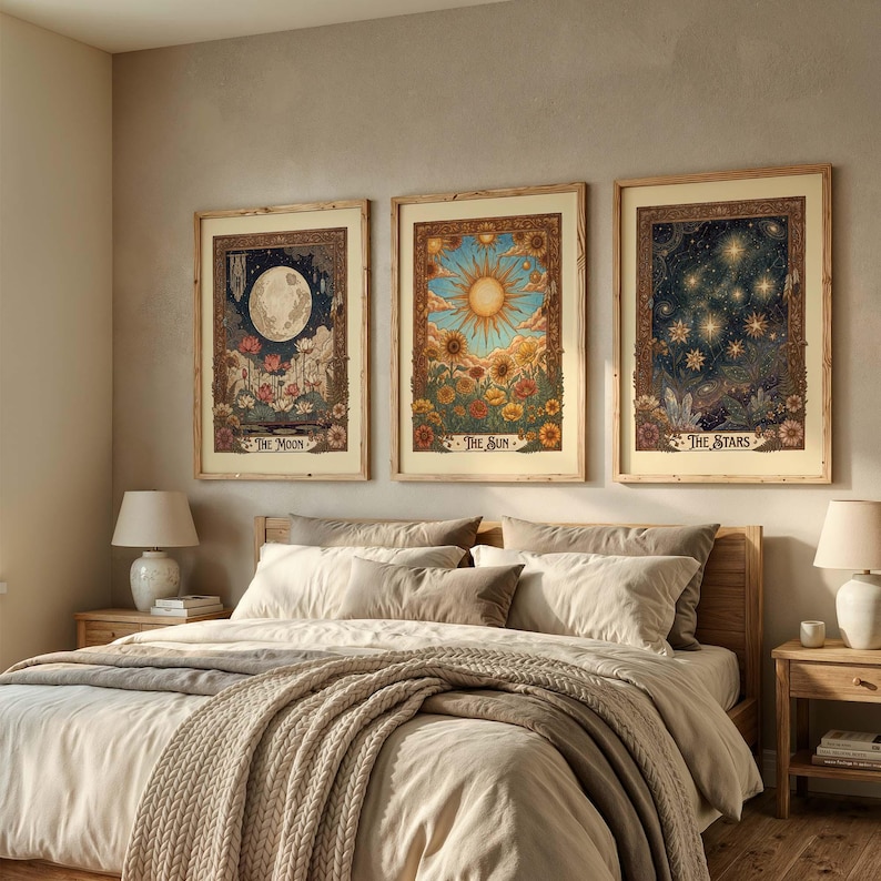 Puede incluir: Tres impresiones art&iacute;sticas celestiales enmarcadas: "La Luna", "El Sol" y "Las Estrellas". Cada una presenta ilustraciones detalladas con bordes florales. La obra de arte se exhibe sobre una cama con ropa de cama de tonos neutros y un marco de madera.