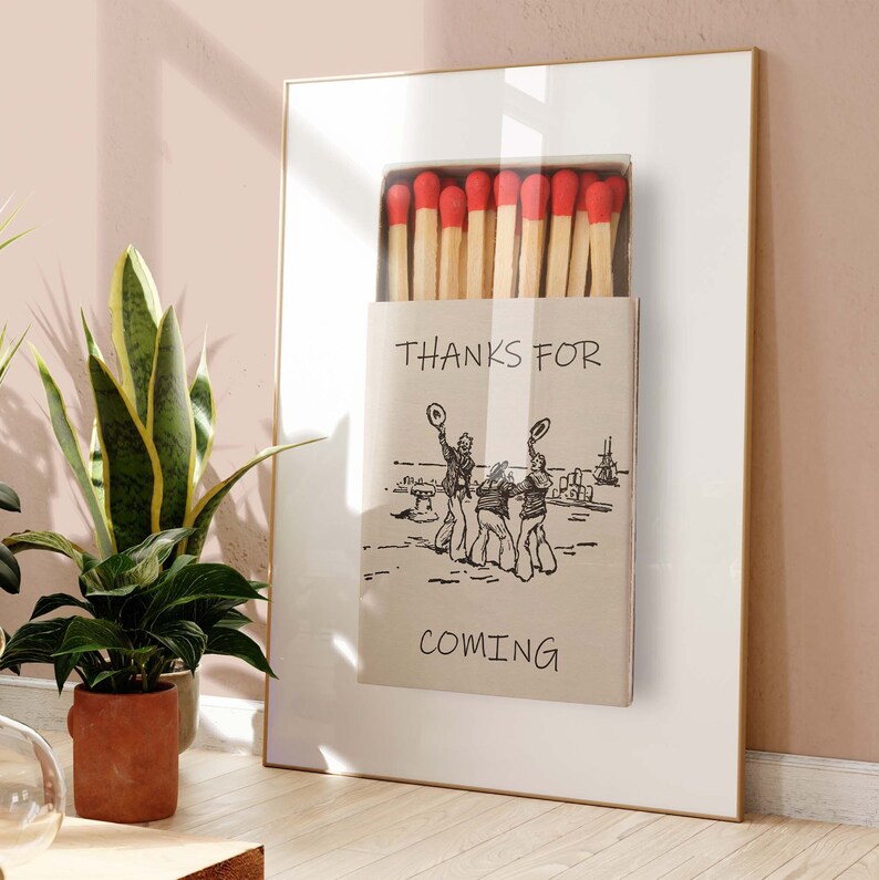 May include: A framed print of a matchbox with the text "Thanks for coming" and a drawing of three people in hats. The matchbox is filled with red-tipped matches.