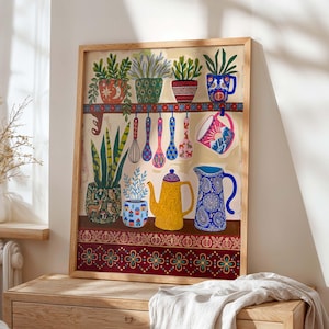 Puede incluir: Una impresión artística enmarcada que representa una escena de cocina con plantas en macetas, utensilios colgantes y una tetera amarilla. La obra de arte tiene una paleta de colores cálidos con patrones decorativos y un marco de madera. Incluye una jarra azul con diseño de cachemira.