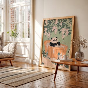 Op de afbeelding: Een ingelijste illustratie van een pandabeer die een bad neemt in een houten badkuip omringd door roze bloemen. De panda heeft een ontspannen uitdrukking en is omringd door bubbels. De illustratie is in traditionele Japanse stijl.