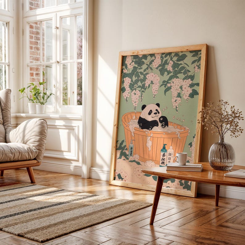 Op de afbeelding: Een ingelijste illustratie van een pandabeer die een bad neemt in een houten badkuip omringd door roze bloemen. De panda heeft een ontspannen uitdrukking en is omringd door bubbels. De illustratie is in traditionele Japanse stijl.