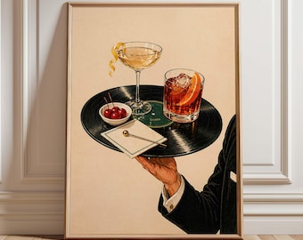 May include: A framed print featuring a vintage-style illustration of cocktails. A hand holds a vinyl record tray with a coupe glass, a rocks glass with an orange slice, cherries, and a cocktail napkin. The background is a neutral beige.