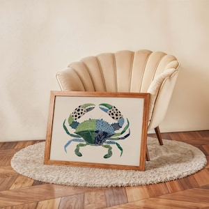 May include: A framed art print featuring a stylized crab illustration. The crab is depicted in shades of green and blue with black and white spotted claws. The artwork is displayed on a cream-colored background within a wooden frame.