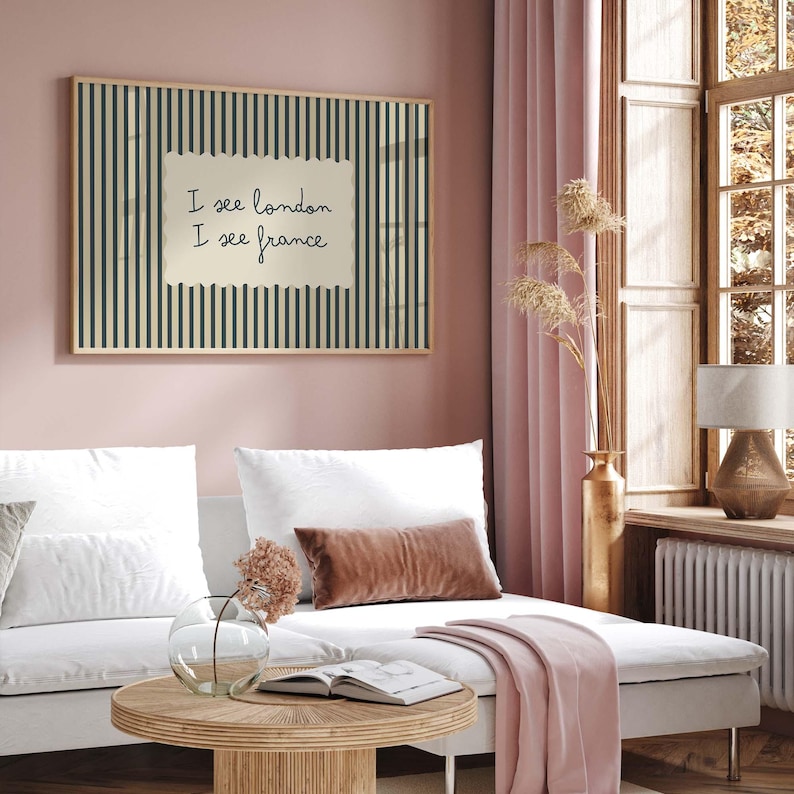 May include: A rectangular wall art print featuring a vertical dark blue and cream striped pattern with a central cream-colored rectangular inset containing the handwritten black text I see london I see france in a simple sans-serif font style.