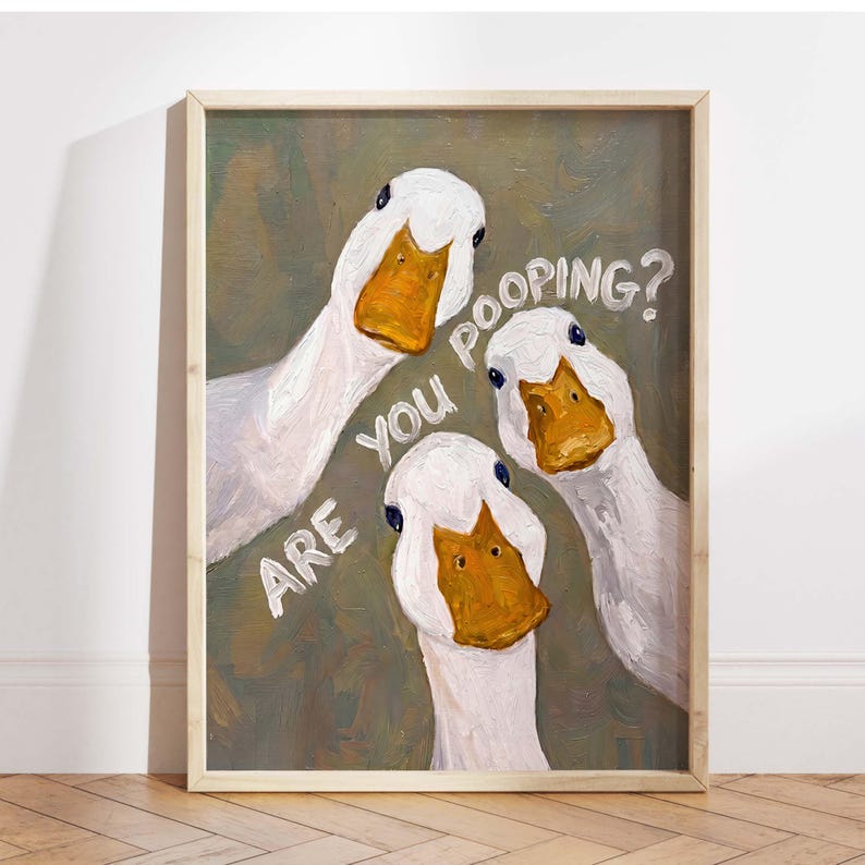 May include: An oil painting in a light wood frame featuring three white ducks with orange beaks against a muted olive green background. The text "ARE YOU POOPING?" is written in white capital letters across the center of the canvas.