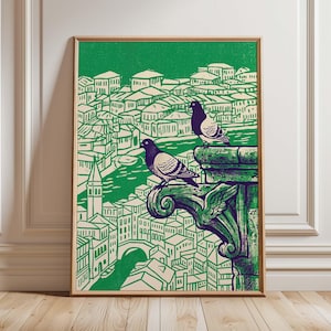 May include: A framed art print featuring two pigeons perched on a green architectural element, overlooking a cityscape. The print uses a green and beige color palette, with a detailed illustration style. The artwork is displayed in a wooden frame.