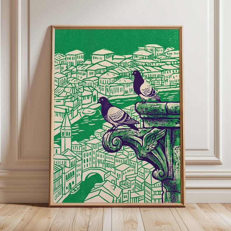May include: A framed art print featuring two pigeons perched on a green architectural element, overlooking a cityscape. The print uses a green and beige color palette, with a detailed illustration style. The artwork is displayed in a wooden frame.
