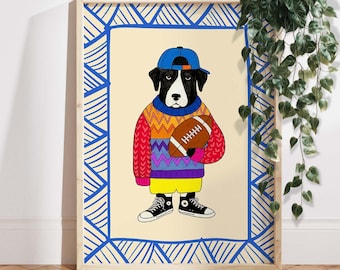 May include: A framed art print featuring a dog wearing a blue baseball cap, a colorful sweater, yellow shorts, and black sneakers, holding a football. The artwork has a blue patterned border and a cream-colored background.