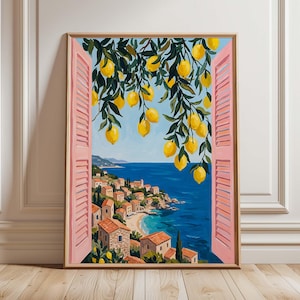 Könnte beinhalten: Ein gerahmter Kunstdruck, der den Blick auf ein mediterranes Küstendorf durch ein offenes Fenster mit rosafarbenen Fensterläden zeigt. Im Vordergrund hängen leuchtend gelbe Zitronen an grünen Zweigen über einem blauen Meer und kleinen Häusern.