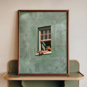 May include: A framed painting depicts a person relaxing in a window, reading a book. The artwork features a green wall with a window and a person's feet and hands holding a book. The frame is brown.