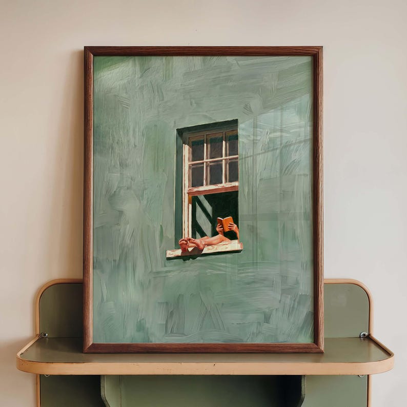 May include: A framed painting depicts a person relaxing in a window, reading a book. The artwork features a green wall with a window and a person's feet and hands holding a book. The frame is brown.