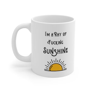 May include: White ceramic mug with a black graphic that reads "I'm a ray of fucking sunshine" with a yellow sun graphic below the text.