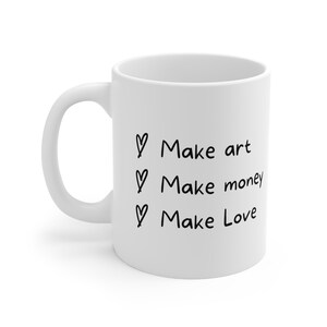 May include: White ceramic coffee mug with black text that reads "Make art, Make money, Make Love" with a heart symbol before each phrase.