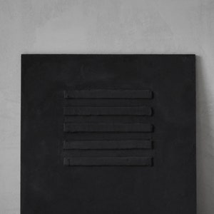 Puede incluir: Un lienzo cuadrado negro con un dise&ntilde;o en relieve de seis l&iacute;neas horizontales.