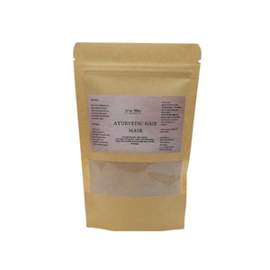 May include: A brown paper pouch with a clear window showing a brown powder inside. The pouch has a white label with the text "LUNA SHA - art of beauty" and "AYURVEDIC HAIR MASK" in black text. The label also includes instructions for use and ingredients.