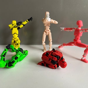 May include: Four articulated action figures in different poses. The figures are made of plastic and are painted in various colors, including yellow, green, red, and skin tone.