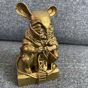 May include: A gold-coloured figurine of a mouse wearing glasses and a robe, holding a strand of DNA. The mouse is sitting on a gold-coloured base with a ladder.