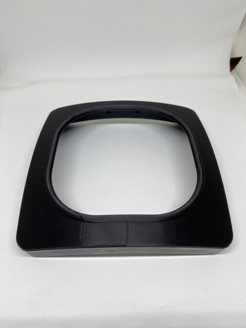 May include: A black plastic frame with a rounded opening, likely for a phone or other device.