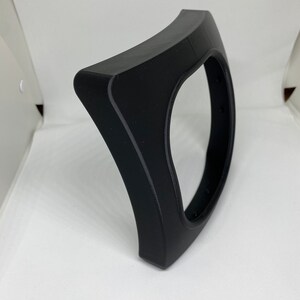 May include: A black plastic curved frame with a circular opening in the center. The frame is designed to hold a round object, such as a clock or a mirror.