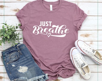 May include: A mauve t-shirt with the text "Just Breathe" in white lettering with a small heart graphic.