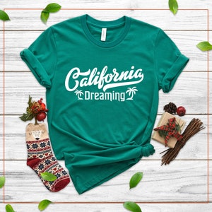 May include: A teal green t-shirt with white text that reads "California Dreaming" with palm tree graphics.