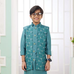 May include: A young person wearing a teal blue kurta with a matching embroidered vest. The kurta has a mandarin collar and button closure. The person is wearing white pants and black sneakers.