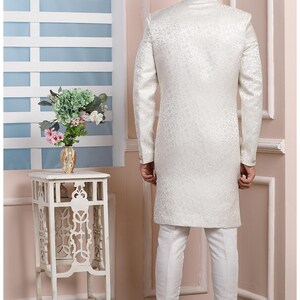Puede incluir: Una kurta blanca de manga larga con un sutil estampado floral. La kurta tiene un cuello mandar&iacute;n y cierre de bot&oacute;n. El modelo lleva pantalones blancos.