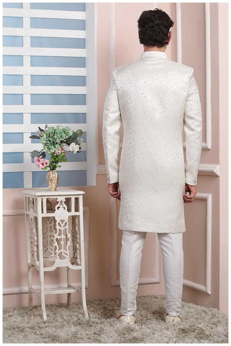 Puede incluir: Una kurta blanca de manga larga con un sutil estampado floral. La kurta tiene un cuello mandar&iacute;n y cierre de bot&oacute;n. El modelo lleva pantalones blancos.