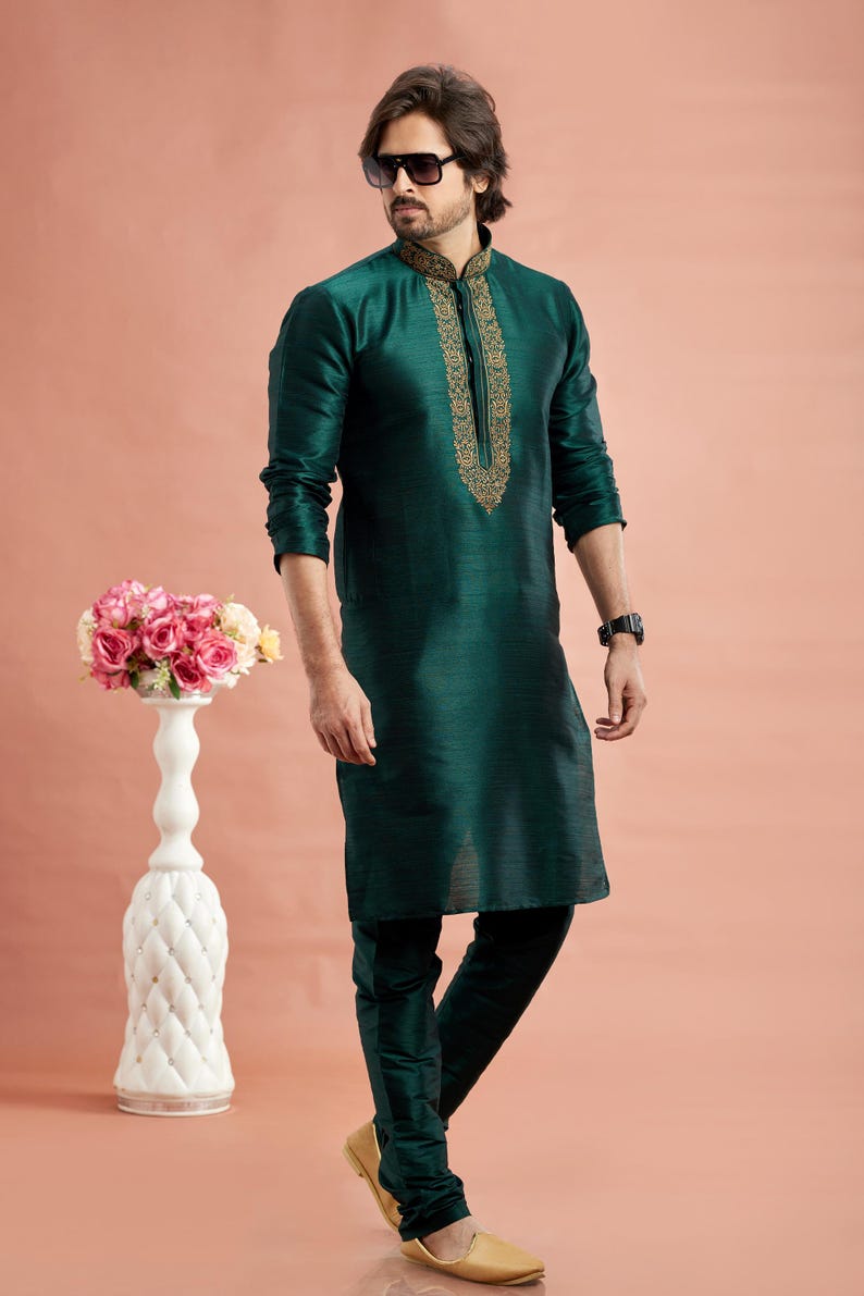 May include: A dark teal kurta pajama set. The long-sleeved kurta features gold embroidery around the collar and down the front. The matching pajama pants are a similar dark teal color. The person is wearing sunglasses and gold-colored shoes.