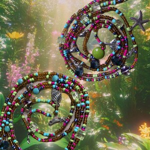 Puede incluir: Dos cadenas de cintura con cuentas en forma de espiral con una variedad de cuentas coloridas. Las cadenas presentan cuentas marrones, rosas, azules y verdes, junto con dijes decorativos como conchas marinas y estrellas de mar. El fondo es una imagen borrosa de un jardín.