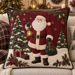 May include: A square quilted throw pillow featuring a central Santa Claus figure holding a lit lantern and a dark green sack. The design includes snow-covered pine trees, wrapped gifts, holly berries, pinecones, and gold bells on a deep red background.