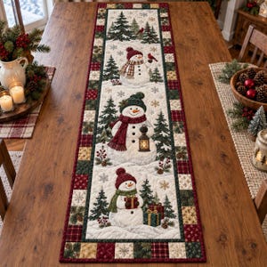 Peut inclure: Un chemin de table matelassé rectangulaire avec un panneau central crème orné de trois bonhommes de neige, de sapins et de flocons. Les bonhommes portent des bonnets et écharpes, tenant une lanterne et des cadeaux. Bordure en patchwork rouge et vert.