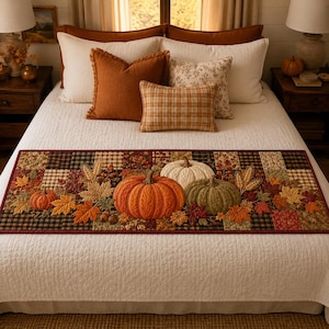 May include: A rectangular quilted table runner featuring a patchwork design of black, brown, and cream squares. The runner is decorated with fabric appliques of orange, white, and green pumpkins, autumn leaves, wheat stalks, and small acorns.