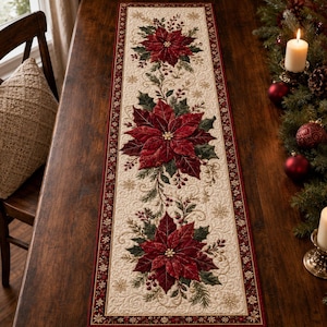 Puede incluir: Un camino de mesa rectangular con una base de tela acolchada de color crema y un patrón repetitivo de flores de pascua de color rojo intenso, hojas de acebo verdes y pequeñas bayas rojas. Tiene un borde rojo oscuro con copos de nieve dorados.