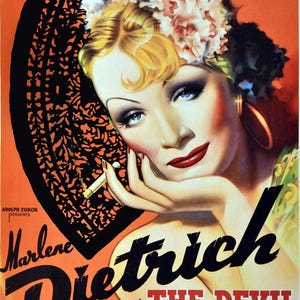 May include: Vintage movie poster for "The Devil Is A Woman" featuring Marlene Dietrich. The poster has an orange background with a black lace fan and a close-up of Dietrich with blonde hair, blue eyes, and red lipstick. The film title and credits are also visible.