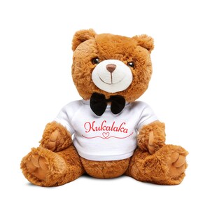 May include: A brown teddy bear with a black bow tie and a white t-shirt. The t-shirt has the word "Kukalaka" in red script with a heart symbol. The bear is sitting with its arms and legs spread.