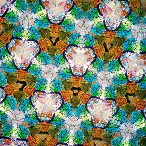 May include: Abstract kaleidoscope pattern with a repeating design of blue, green, orange, and white geometric shapes. The shapes are outlined in black and create a symmetrical pattern.