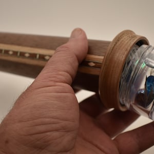 May include: A wooden kaleidoscope with a clear plastic viewing end. The kaleidoscope is decorated with a wood inlay pattern.