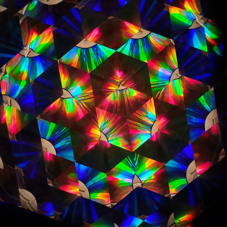 May include: A kaleidoscope image with a repeating pattern of colorful, geometric shapes. The shapes are primarily red, green, blue, and yellow, and they create a sense of depth and movement.