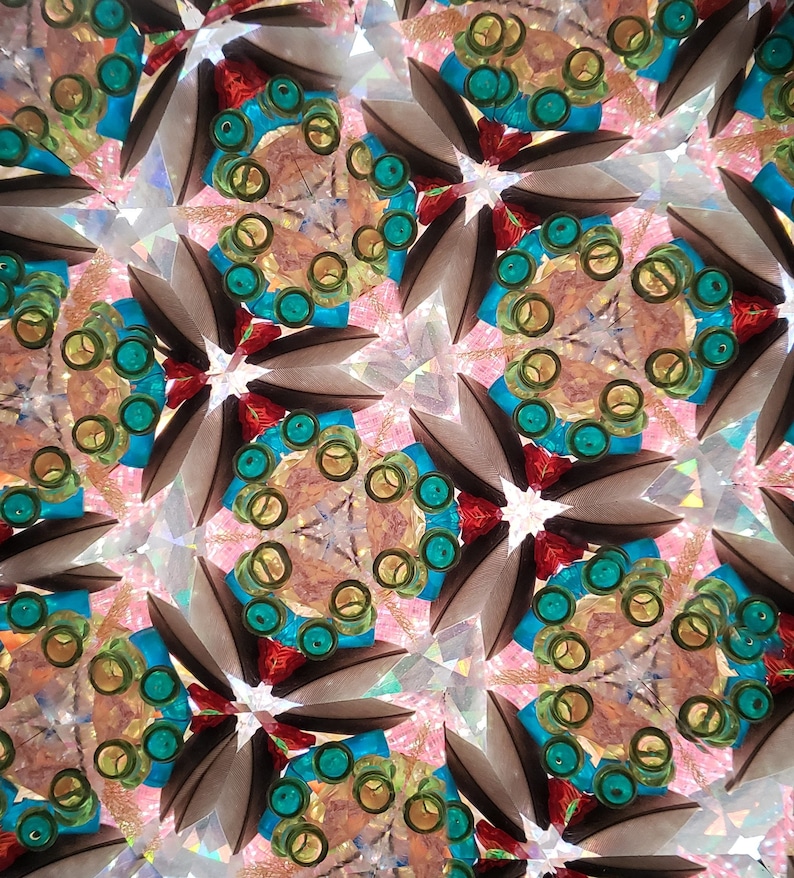 May include: A kaleidoscope image with a repeating pattern of teal, yellow, and red circles. The background is a shimmering, iridescent surface.