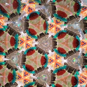 May include: A kaleidoscope image with a repeating pattern of red, orange, and teal shapes. The shapes are arranged in a symmetrical pattern, creating a sense of depth and movement.