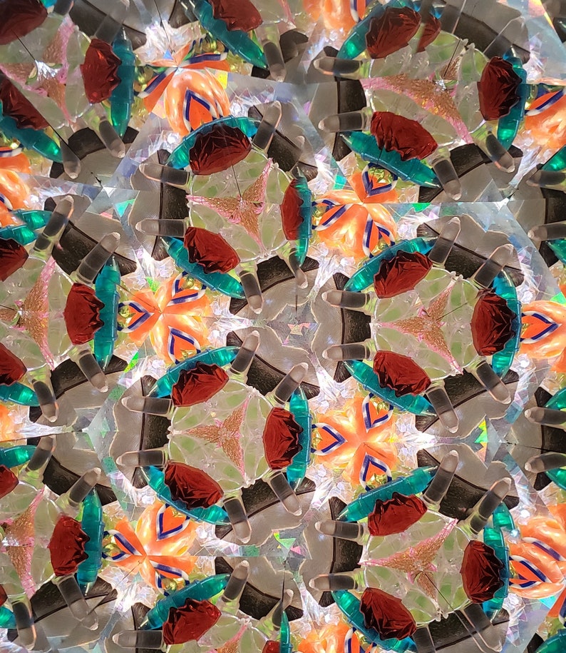 May include: A kaleidoscope image with a repeating pattern of red, orange, and teal shapes. The shapes are arranged in a symmetrical pattern, creating a sense of depth and movement.
